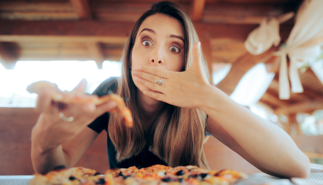 Woman Eating Pizza Feeling Sick Covering her Mouth. Person regretting having a nasty meal in a bad fast-food restaurant