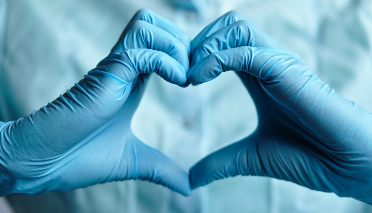 A doctor in blue medical gloves makes a heart out of his hands